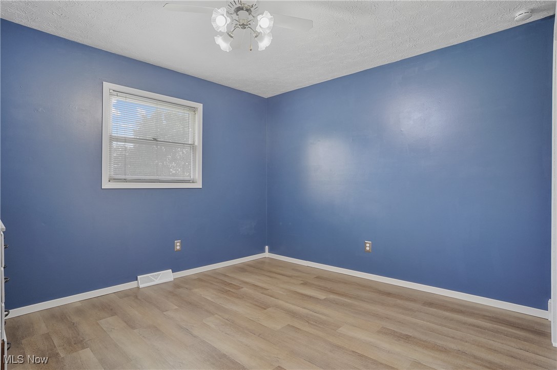 3262 Wright Road Northwest Uniontown, OH 44685 - Photo 24 of 37 Unfurnished room featuring a ceiling fan, light wood-style floors, a smoke detector, and a textured ceiling