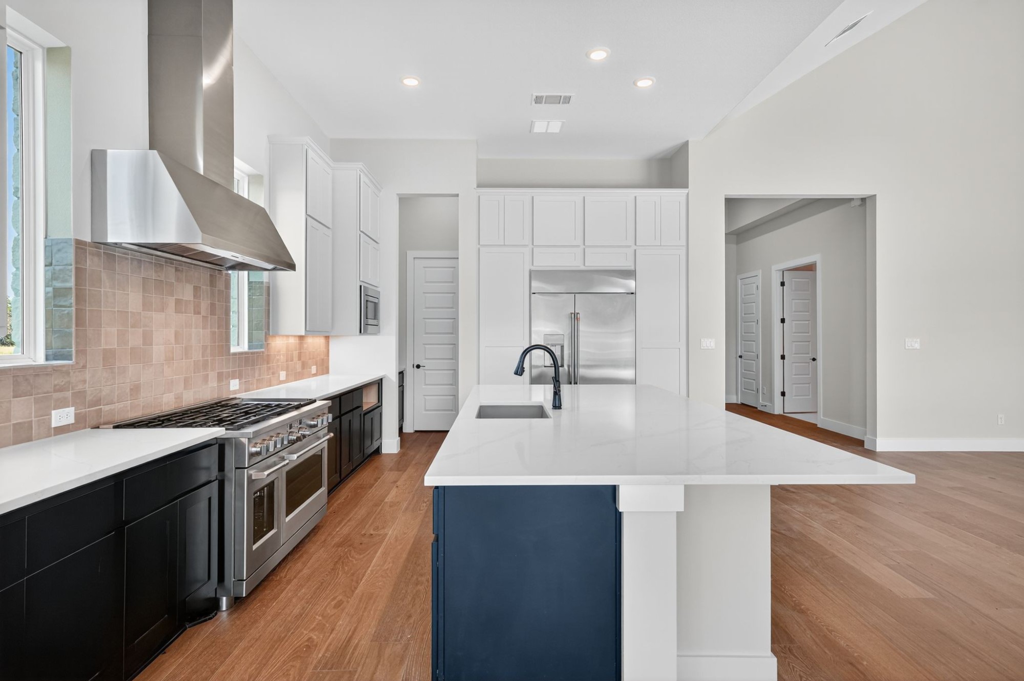 205 Three Rivers Road Georgetown, TX 78633 - Photo 8 of 32 Kitchen with light wood-type flooring, wall chimney exhaust hood, built in appliances, light stone counters, and recessed lighting
