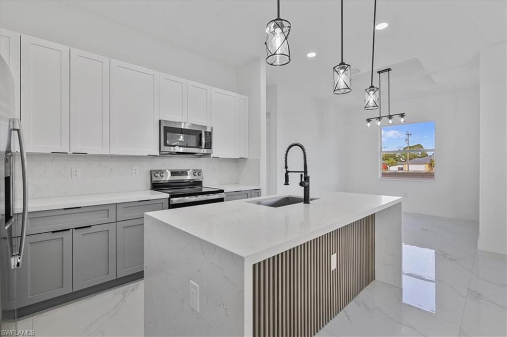 3812 9th Street Southwest Lehigh Acres, FL 33976 - Photo 11 of 39 a kitchen with a sink and a stove top oven with wooden floor