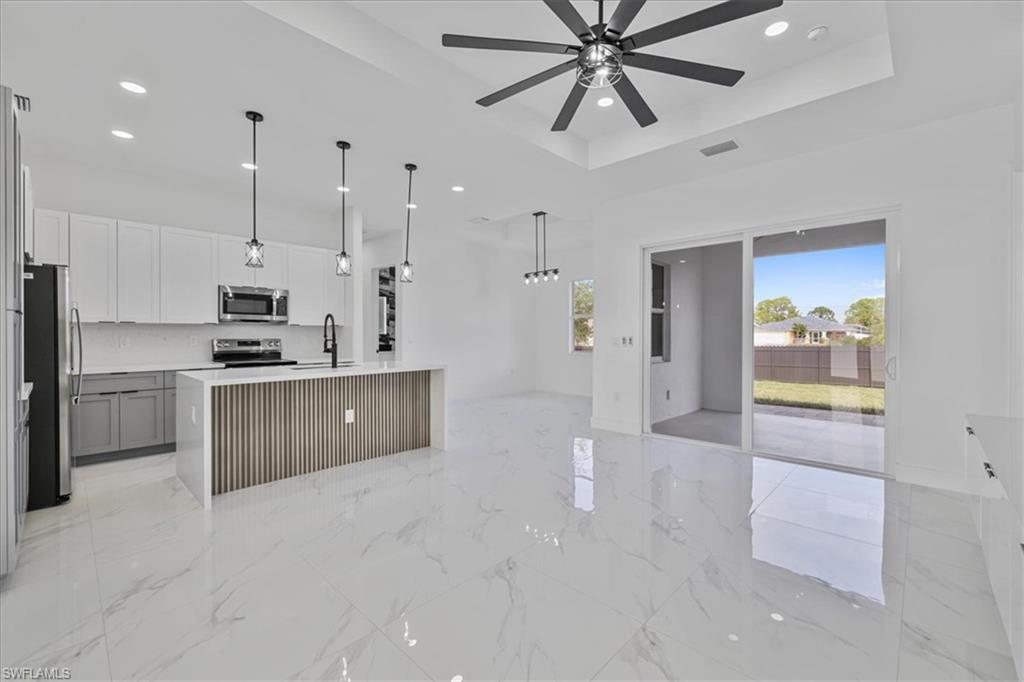 3812 9th Street Southwest Lehigh Acres, FL 33976 - Photo 7 of 39 a kitchen with kitchen island white cabinets and stainless steel appliances