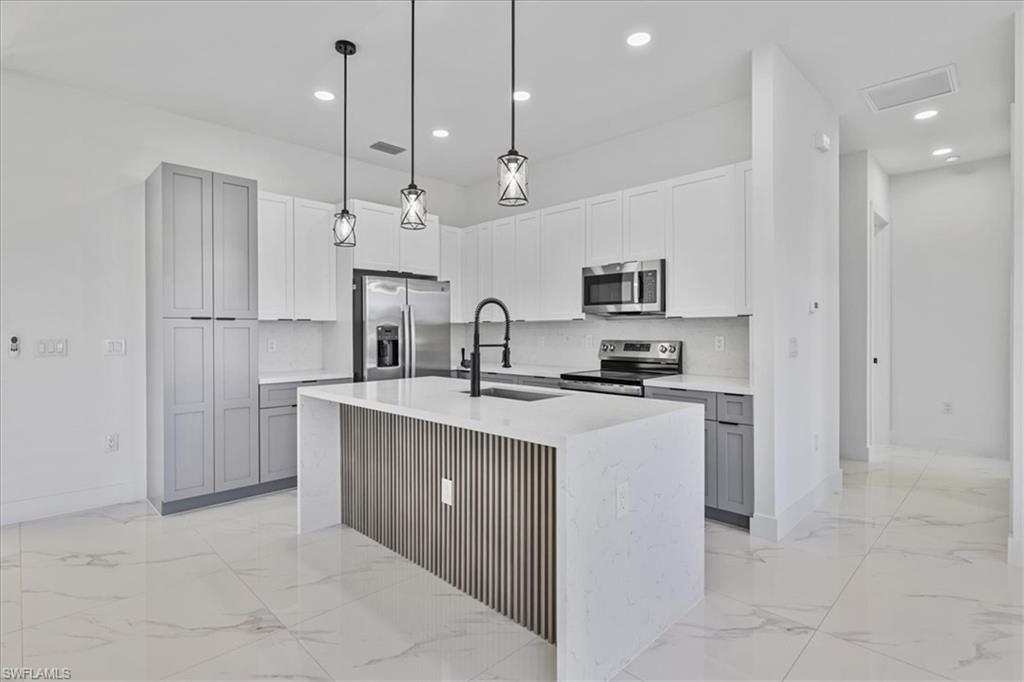 3812 9th Street Southwest Lehigh Acres, FL 33976 - Photo 8 of 39 a kitchen with kitchen island a sink stainless steel appliances and cabinets