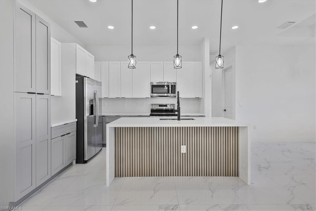 3812 9th Street Southwest Lehigh Acres, FL 33976 - Photo 9 of 39 a kitchen with kitchen island a refrigerator and a sink