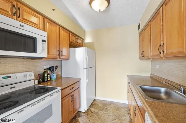 a kitchen with stainless steel appliances granite countertop a sink and a refrigerator
