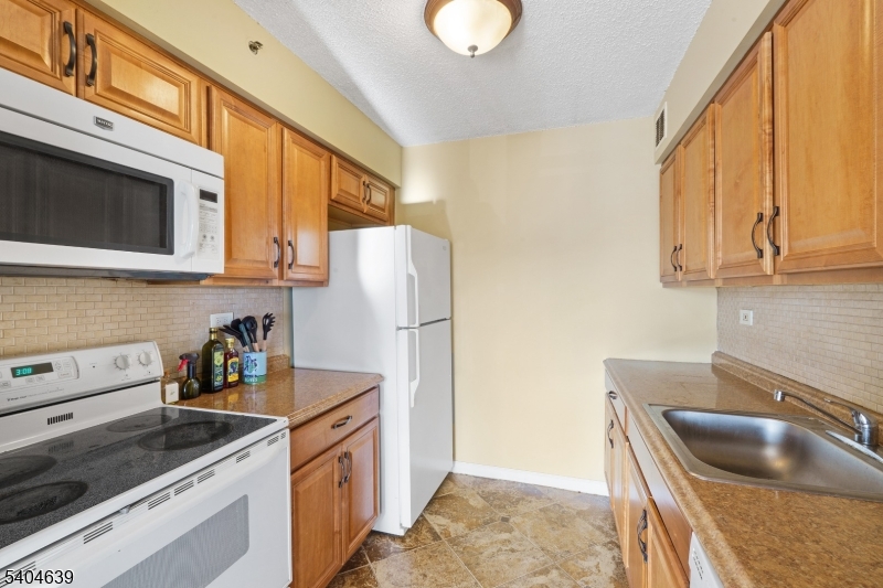 300 Main Street, Unit 416 Little Falls, NJ 07424 - Photo 8 of 19 a kitchen with stainless steel appliances granite countertop a sink and a refrigerator