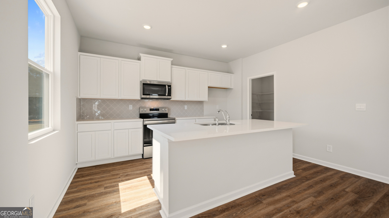 8578 Seabiscuit Road Lithonia, GA 30058 - Photo 10 of 30 a kitchen with a sink a stove a microwave and white cabinets