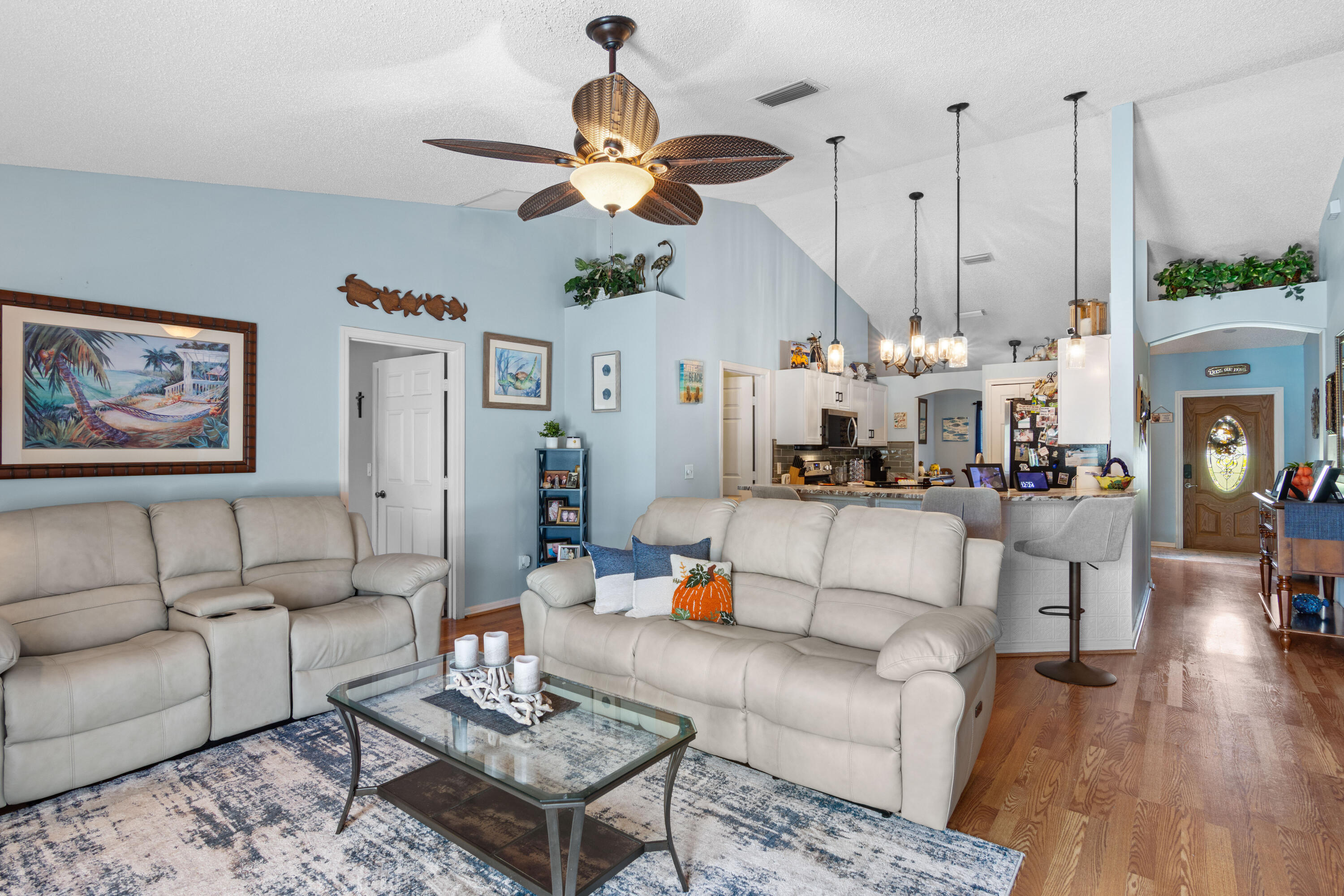 1817 Southwest Davis Street Port St. Lucie, FL 34953 - Photo 12 of 52 a living room with couches a fireplace and kitchen view with wooden floor