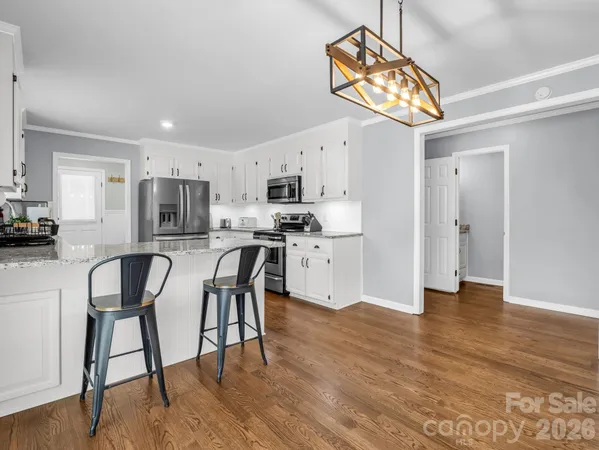 a kitchen with stainless steel appliances a dining table chairs refrigerator and microwave