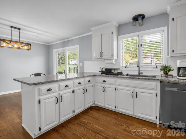 a kitchen with granite countertop white cabinets white appliances a sink and a window