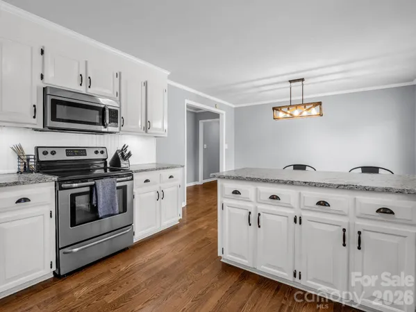 a kitchen with stainless steel appliances granite countertop a sink a stove a microwave and wooden floors