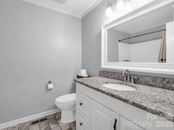 a bathroom with a granite countertop toilet sink mirror and vanity