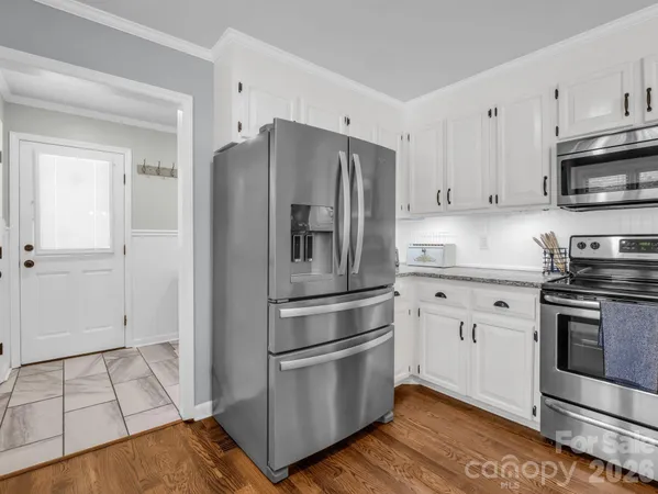 a kitchen with stainless steel appliances granite countertop a refrigerator stove and white cabinets