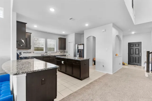 a kitchen with stainless steel appliances granite countertop a refrigerator a sink a stove top oven and a dishwasher