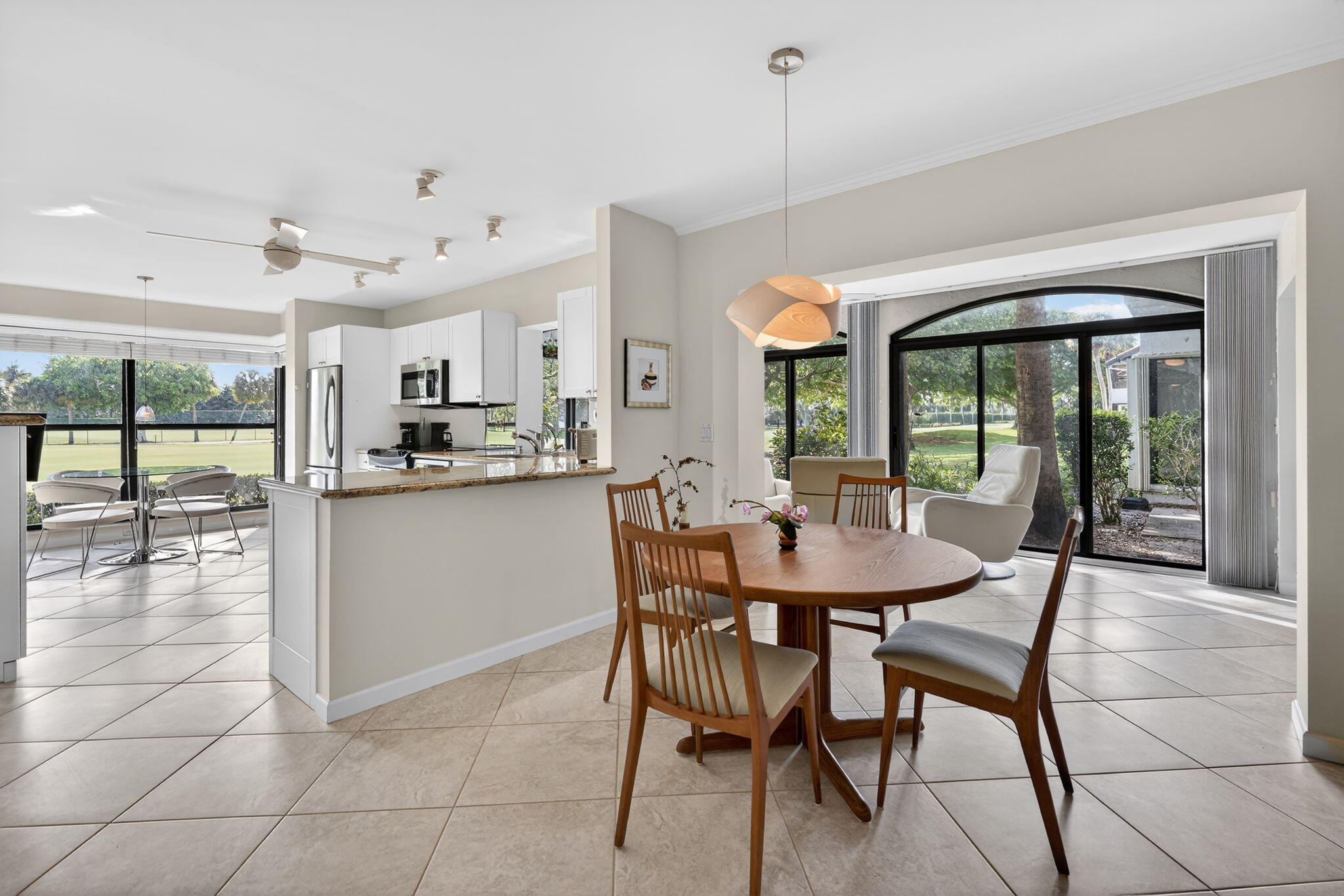 16670 Traders Crossing North, Unit 110 Jupiter, FL 33477 - Photo 10 of 22 a dining room with kitchen island granite countertop a table chairs and a chandelier