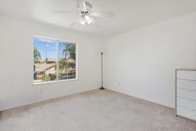 an empty room with windows and fan