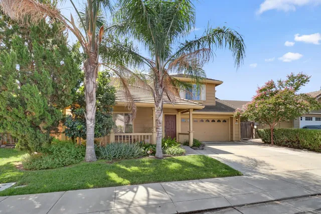 a front view of a house with a garden and palm trees