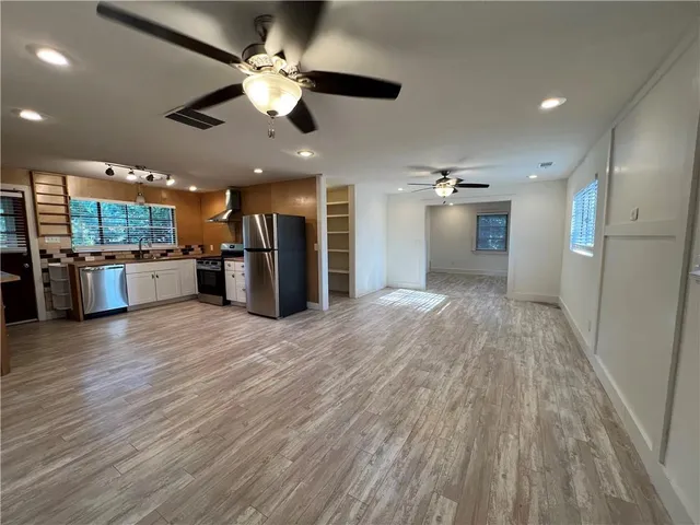 an open kitchen with a refrigerator and wooden floor