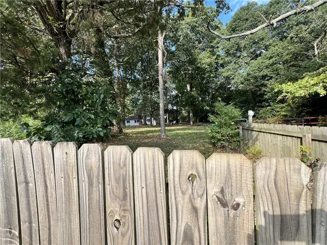 a view of a white house with a small yard and wooden fence