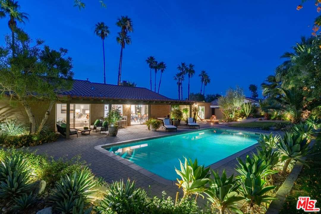 a view of a house with table and chairs under an umbrella