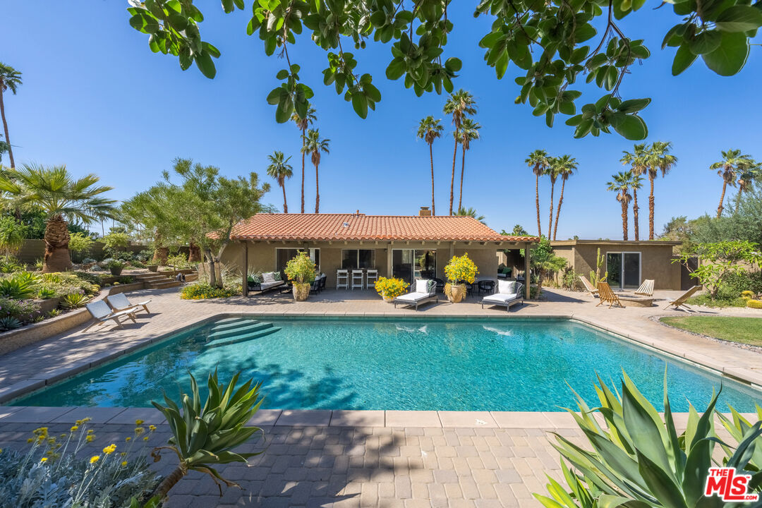 73589 Haystack Road Palm Desert, CA 92260 - Photo 29 of 54 a view of a swimming pool with lawn chairs under an umbrella