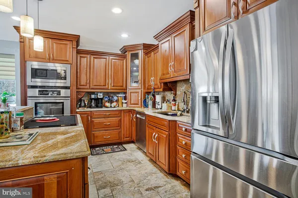 a kitchen with stainless steel appliances granite countertop a refrigerator a stove and a sink