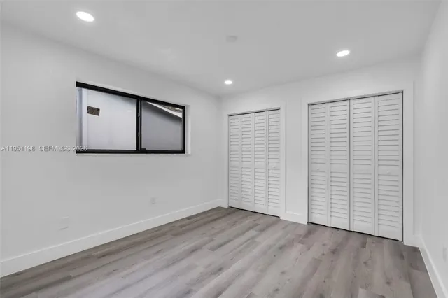 a view of an empty room with wooden floor and closet