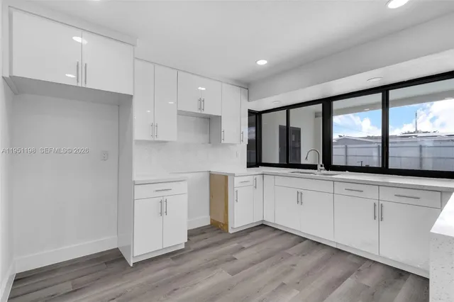 a kitchen with stainless steel appliances granite countertop a stove a sink and white cabinets