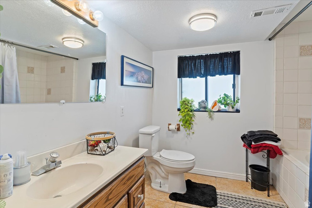5321 South 3100th Street West Roy, UT 84067 - Photo 50 of 64 Bathroom featuring a single-sink vanity with light-colored countertop and wood-finish cabinetry, a window with black privacy curtain, a toilet, and a tiled shower/tub combination