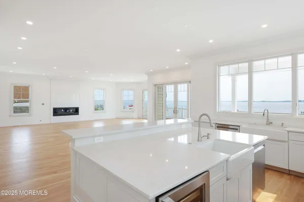 a large kitchen with stainless steel appliances a sink dishwasher and a stove with wooden floor