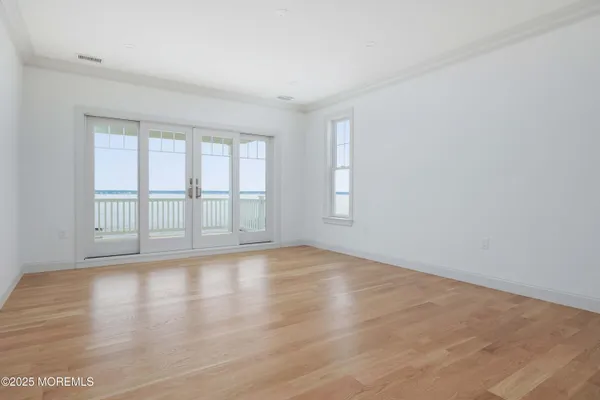 a view of an empty room with wooden floor and window
