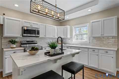 a kitchen with stainless steel appliances a white table chairs and a wooden floor