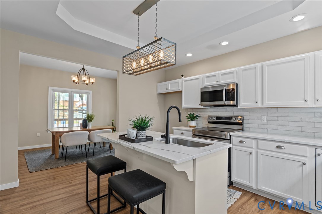 2701 Perdue Avenue Chester, VA 23831 - Photo 12 of 54 a kitchen with stainless steel appliances a white table chairs and a wooden floor
