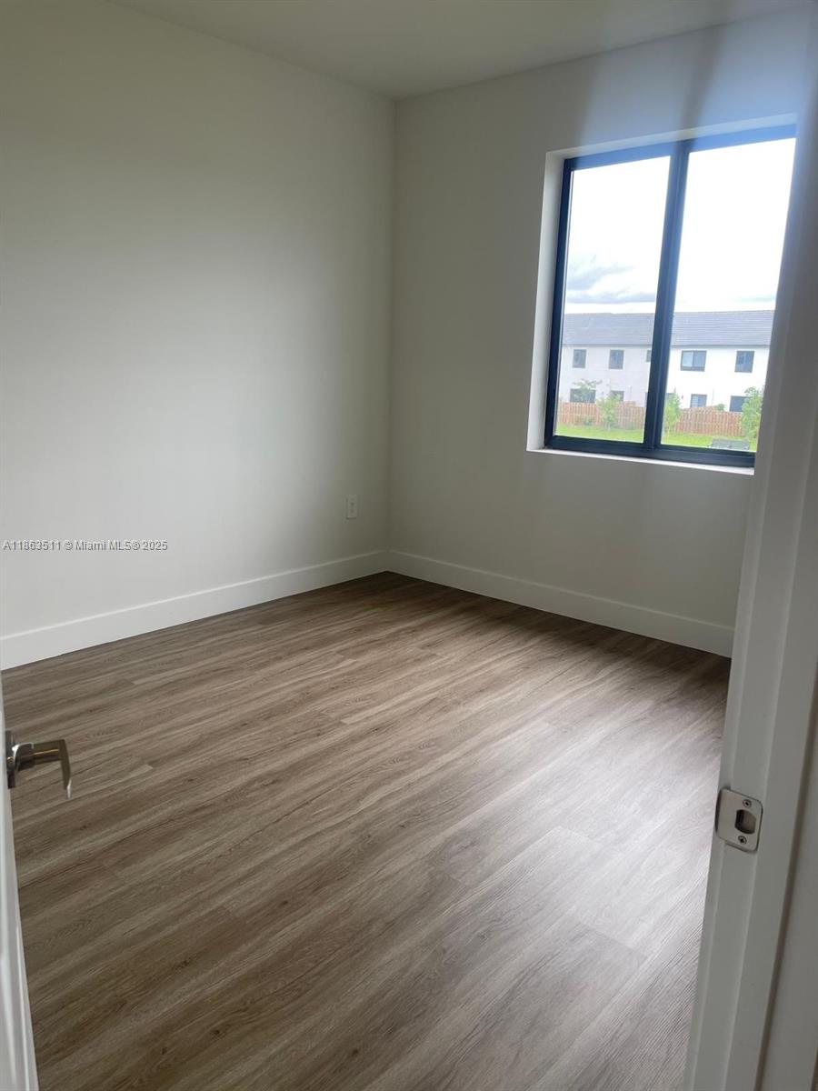 18988 Southwest 344th Terrace Homestead, FL 33034 - Photo 21 of 28 an empty room with wooden floor and windows
