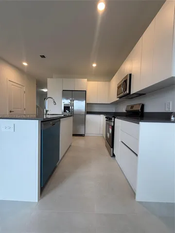 a kitchen with stainless steel appliances granite countertop a sink and a refrigerator