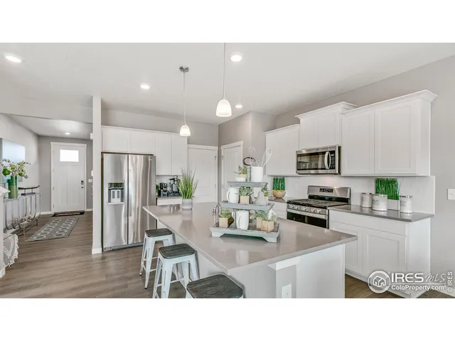a kitchen with stainless steel appliances kitchen island granite countertop a refrigerator a stove top oven a sink dishwasher and white cabinets with wooden floor