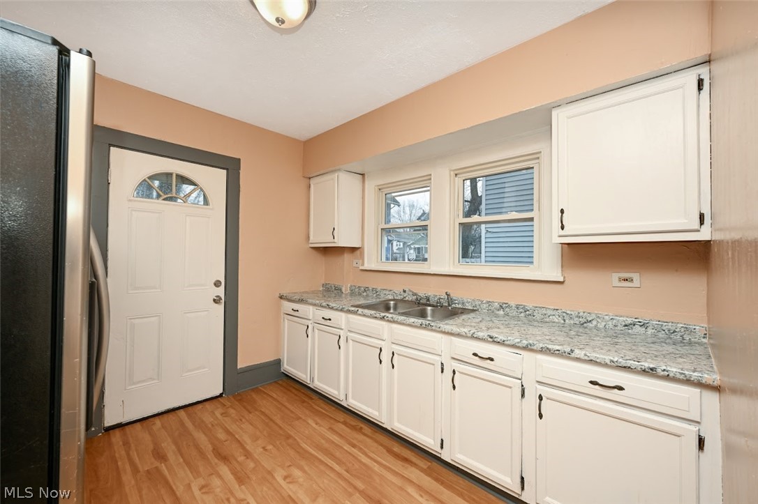 77 West Mildred Avenue Akron, OH 44310 - Photo 13 of 40 Kitchen with freestanding refrigerator, light wood-type flooring, white cabinets, and light stone counters