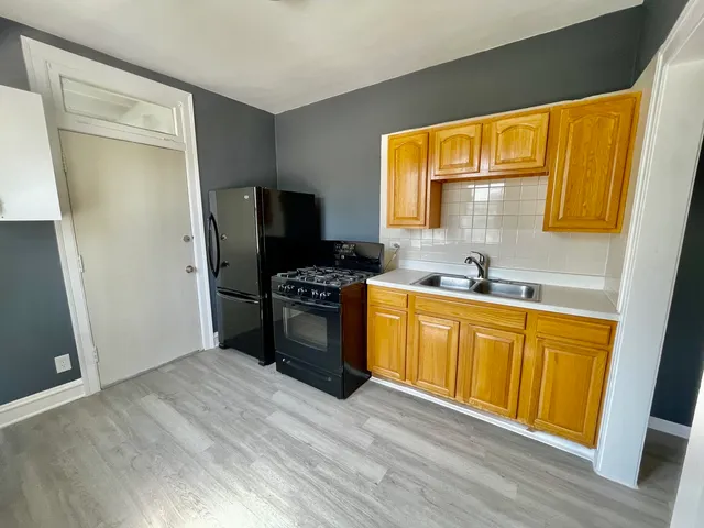 a kitchen with stainless steel appliances kitchen island granite countertop a refrigerator a sink dishwasher and wooden cabinets