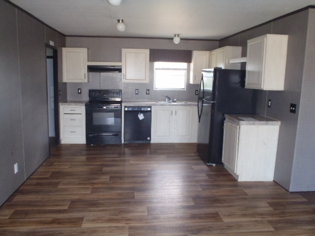 964 Railyard Drive Kyle, TX 78640 - Photo 11 of 25 Kitchen with black appliances, dark wood-type flooring, light countertops, and exhaust hood