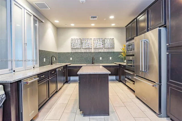 a kitchen with kitchen island a sink stainless steel appliances and cabinets
