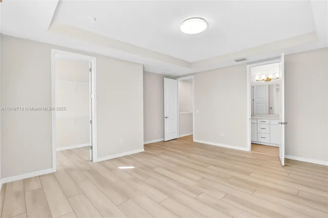 a view of an empty room with wooden floor and a bathroom