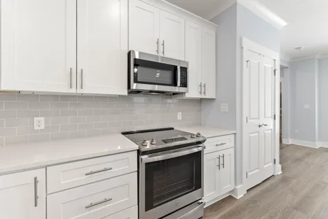 a kitchen with stainless steel appliances white cabinets and a stove a oven with white countertops