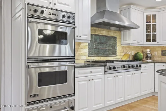 a kitchen with stainless steel appliances granite countertop a stove and a white cabinets