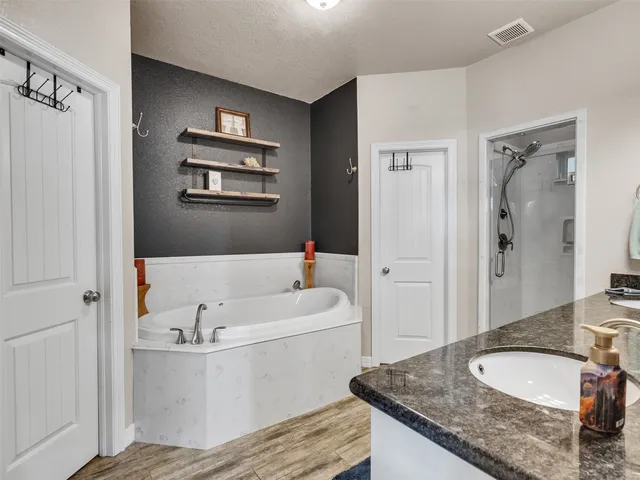 a bathroom with a granite countertop tub sink and mirror
