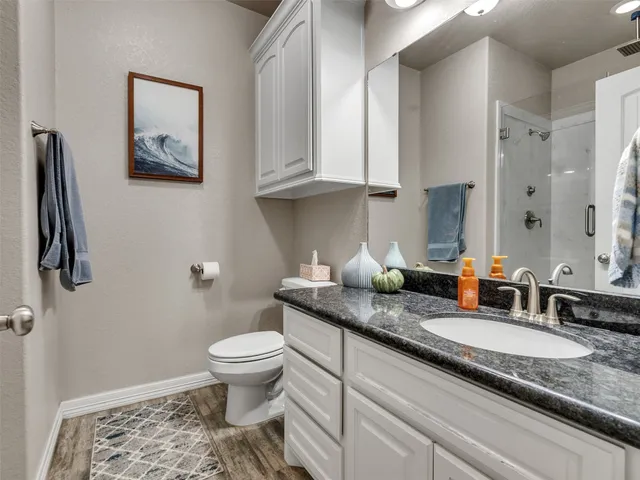 a bathroom with a granite countertop toilet sink and mirror