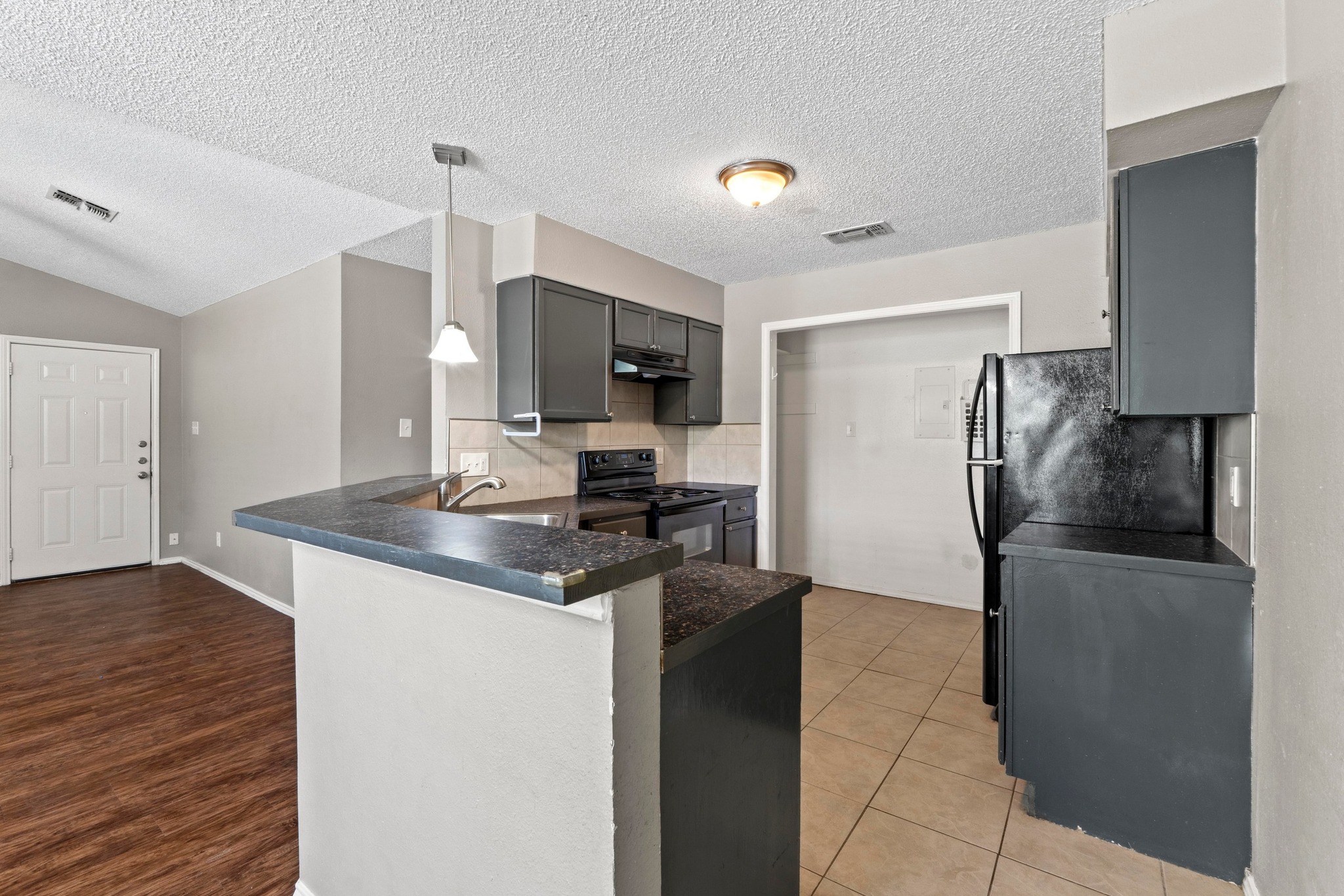 4208 Duval Road, Unit C Austin, TX 78759 - Photo 8 of 28 Kitchen with dark countertops, a peninsula, black appliances, tasteful backsplash, and gray cabinetry