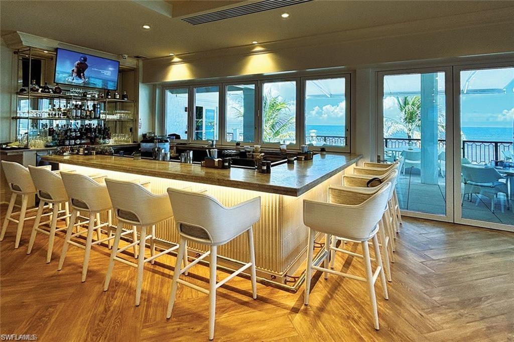 28511 Calabria Court, Unit 202 Naples, FL 34110 - Photo 42 of 44 a dining hall with stainless steel appliances a dining table and chairs with wooden floor