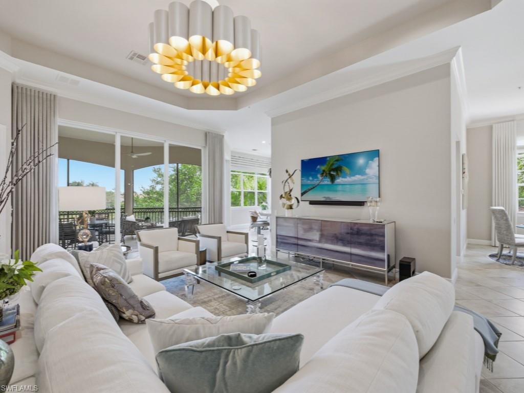 28511 Calabria Court, Unit 202 Naples, FL 34110 - Photo 5 of 44 a living room with furniture a chandelier and a flat screen tv