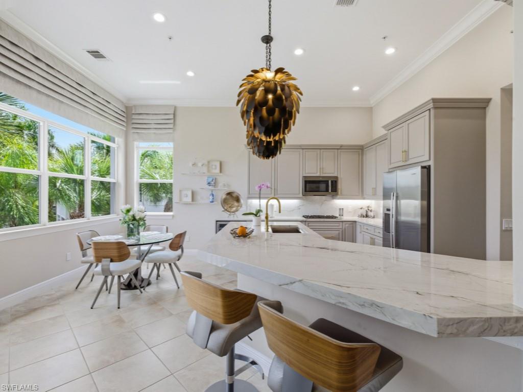 28511 Calabria Court, Unit 202 Naples, FL 34110 - Photo 9 of 44 a dining room with stainless steel appliances granite countertop a dining table chairs and a refrigerator