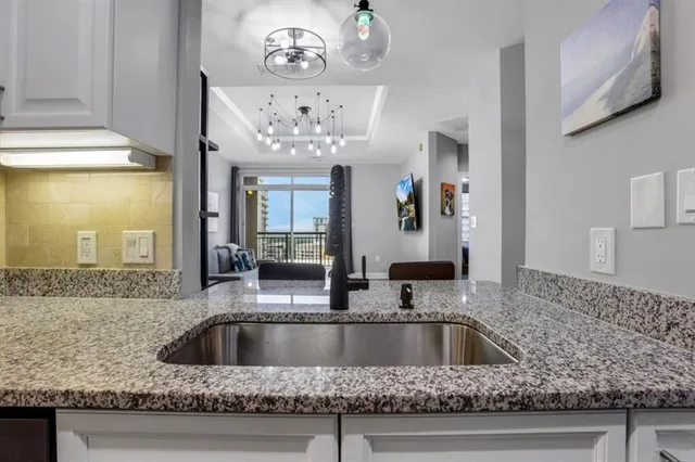 a view with kitchen island a sink granite counter tops and a view of living room