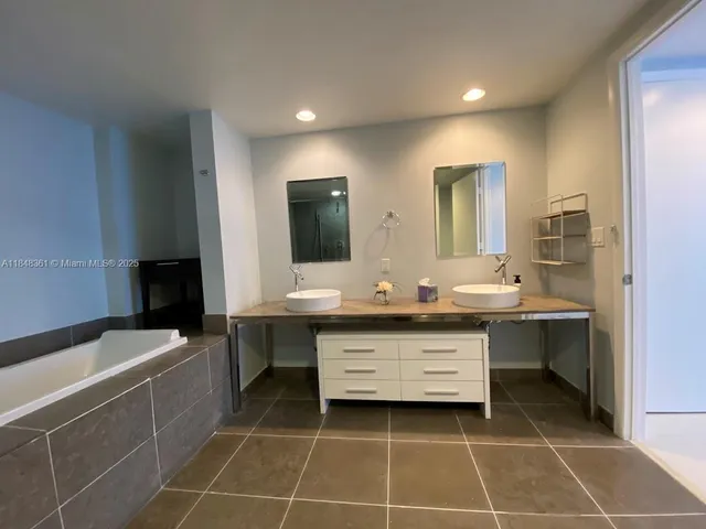 a bathroom with a double vanity sink a mirror and a bathtub