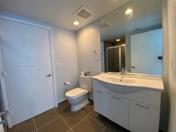 a bathroom with a granite countertop sink mirror vanity and toilet